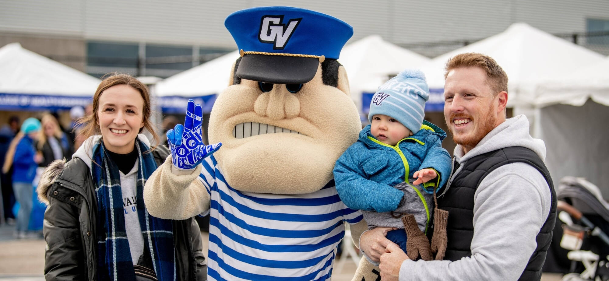 Laker family with young son smile with Louie at Homecoming tailgate